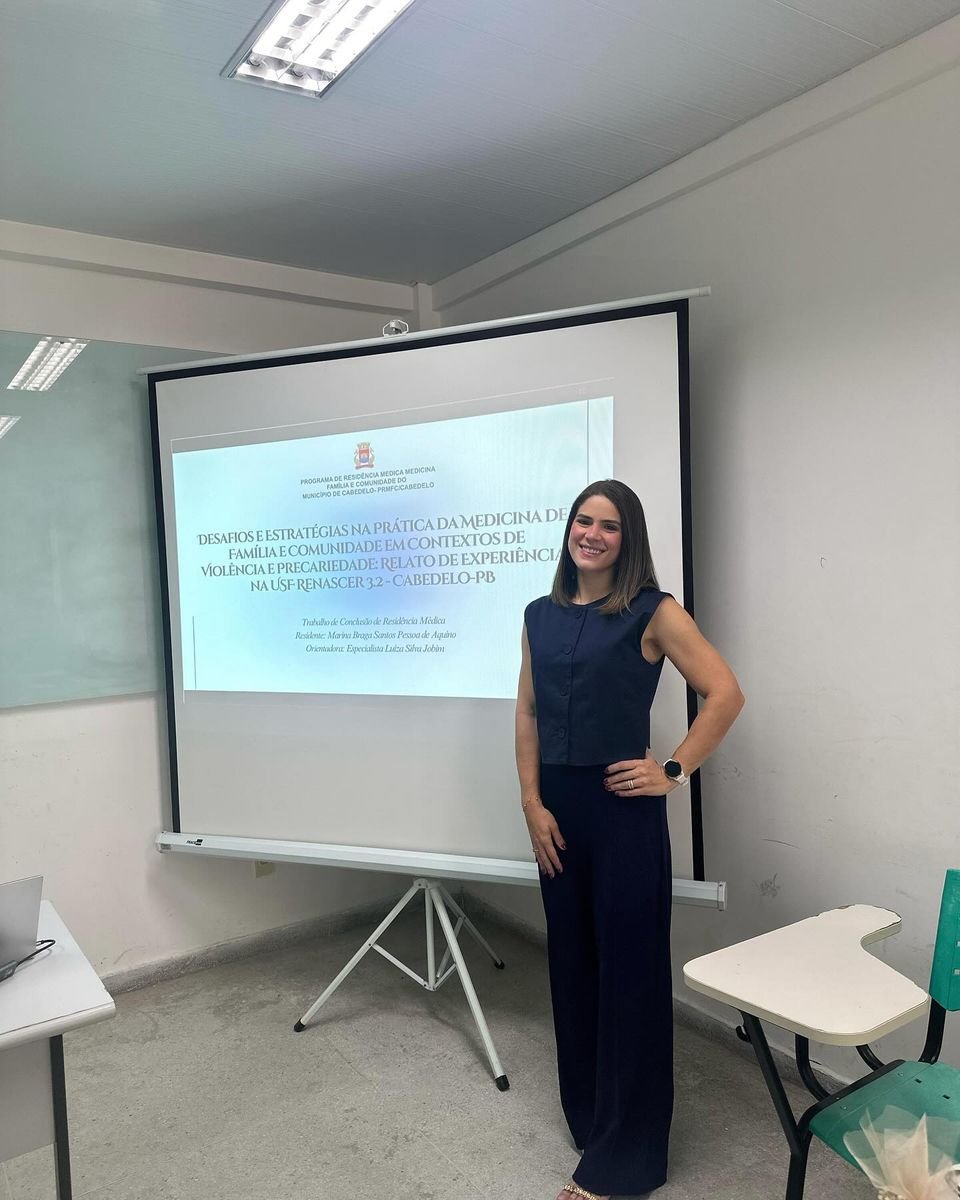 Marina Braga ao lado de uma apresentação acadêmica projetada